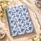 Blue and white iris floral spiral notebook styled on a bright spring Cottagecore wooden desk with blossom branches and botanical accessories