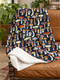 Mushroom Sherpa fleece blanket with colourful woodland toadstools on a dark navy background draped over a brown leather chair