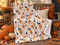Halloween velveteen plush blanket with pumpkins, bats, black cats, ghosts and autumn leaves draped over a rustic wooden bench with autumn cushions and pumpkins