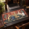 Long medieval tapestry desk mat featuring a unicorn, lion, courtly figures and a central fountain on a dark wooden study desk