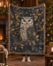 A person holds up a large woven throw blanket featuring a detailed owl and holly pattern in dark blue, gold, and cream tones, with fringed edges, set against a cosy Christmas living room background.