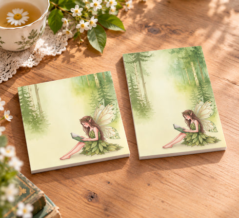 Two Reading Fairy Post-it note pads in different sizes featuring a woodland fairy reading a book, styled on a sunlit spring cottagecore wooden desk