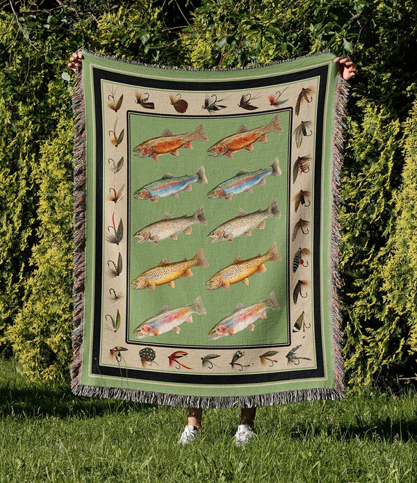 Woven cotton blanket featuring rows of vintage trout illustrations with fishing flies around the border in sage green and cream