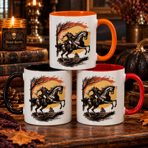 Three ceramic mugs arranged in a pyramid on a wooden table, each printed with a headless horseman equestrian rider graphic against an orange and yellow moon and sky. The mugs have different handle and rim colors: one orange handle, one red handle, and one black handle.